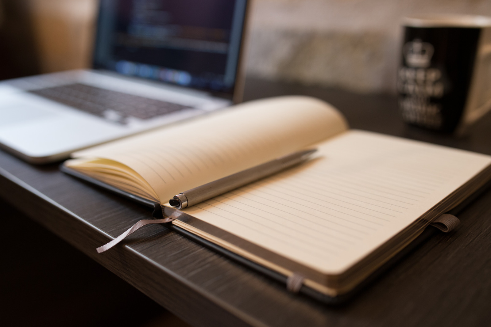 open notebook with pen alongside a computer