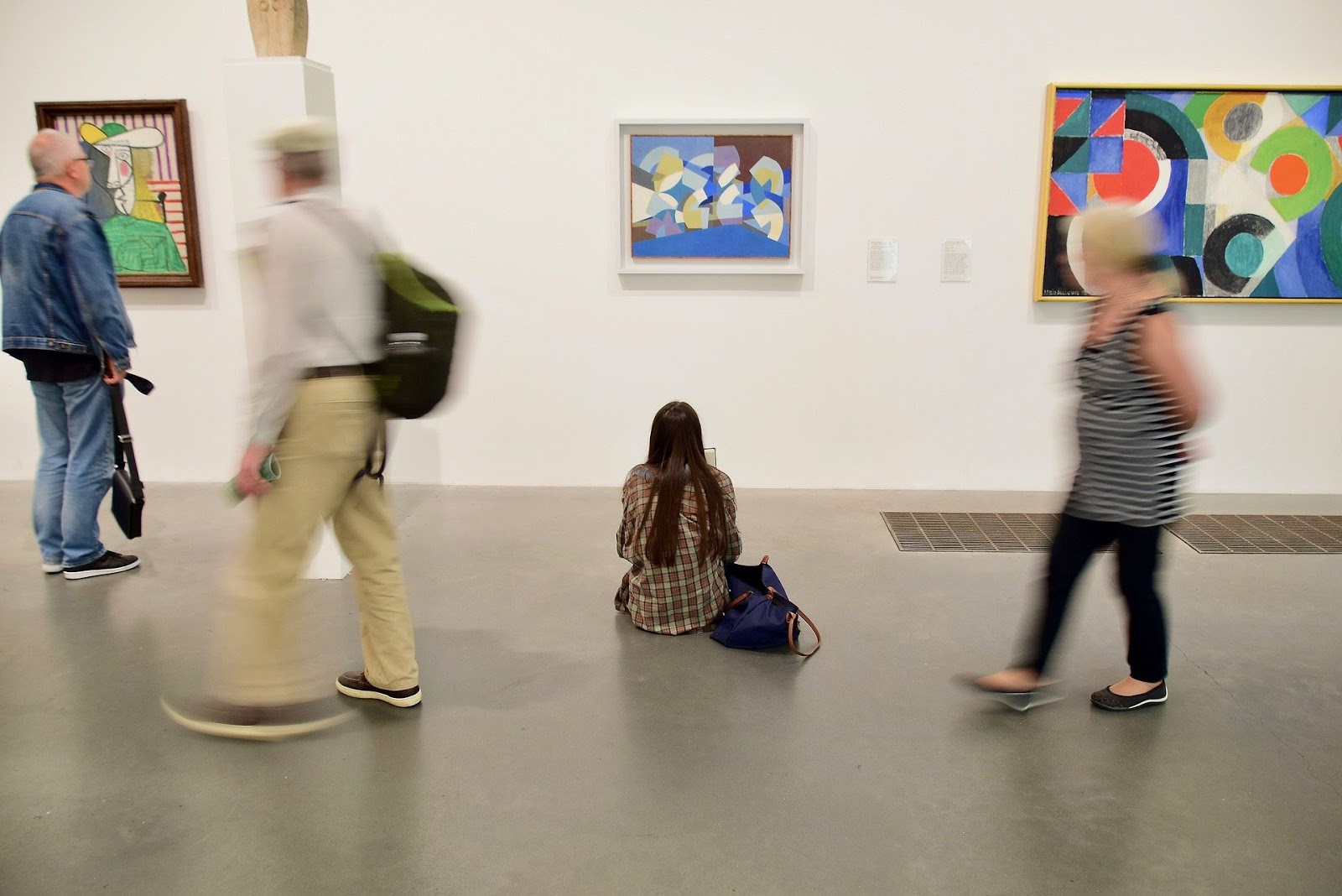 an image of an art gallary with people walking and admiring