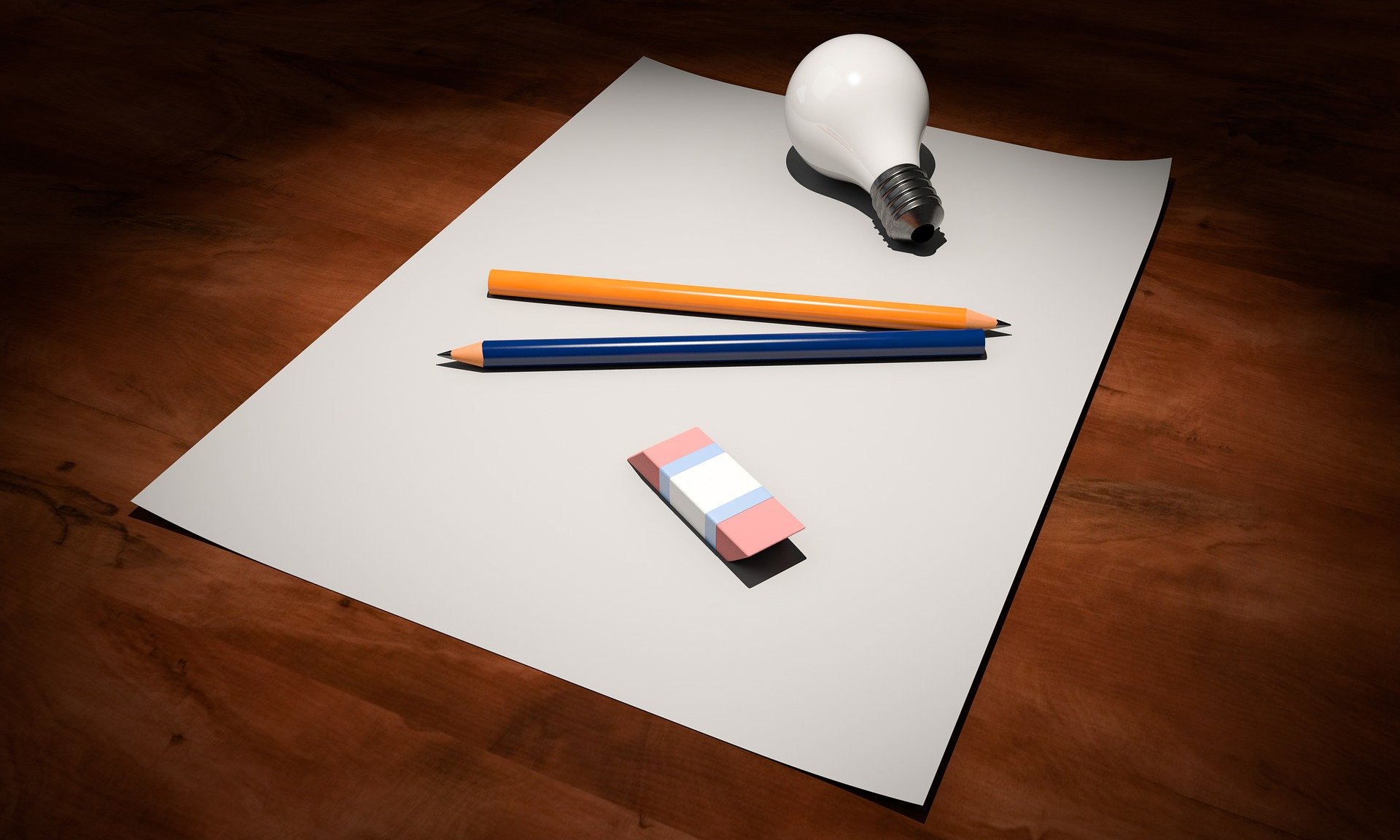 notebook with pencils, eraser, and light bulb laying on a desk