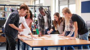 students stand around a table, discussing an active-learning assignment